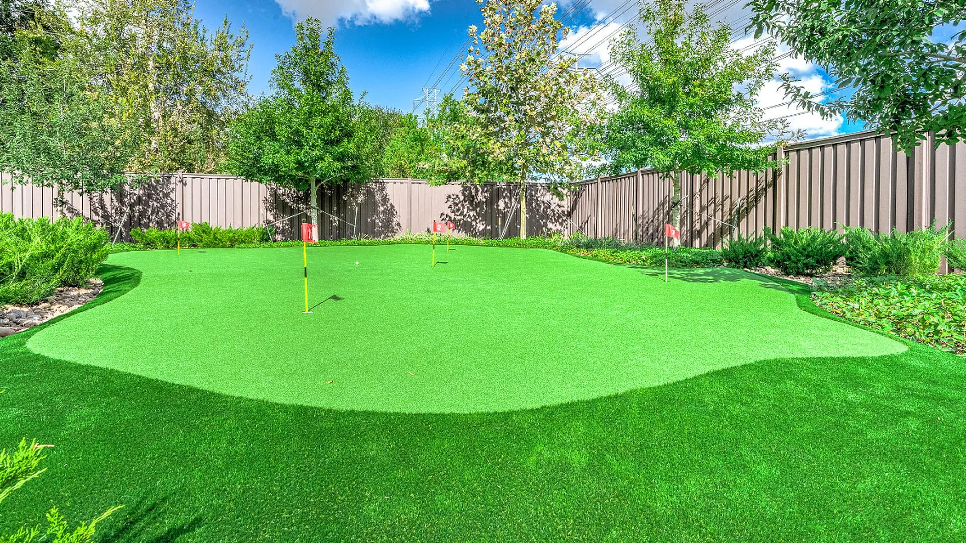 Backyard artificial putting green with flagsticks surrounded by turf in Houston, TX