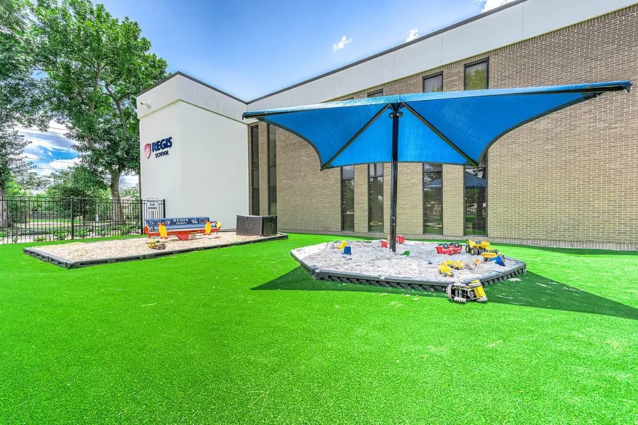 School playground with shade structure and sandbox on bright artificial turf